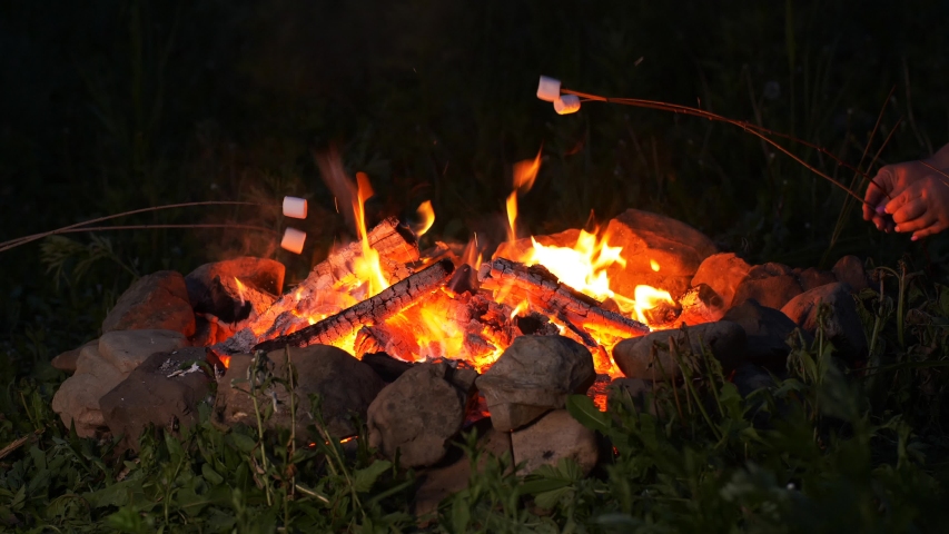 Roasting marshmallow over the campfire at night, taken with a fast prime lens in UHD Royalty-Free Stock Footage #1054120679