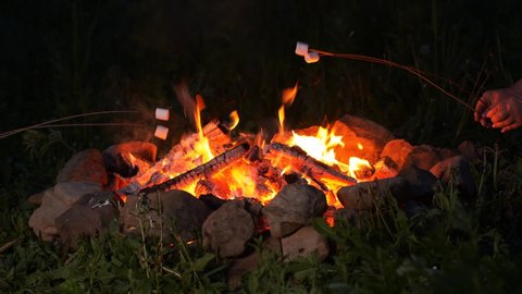Roasting marshmallow over the campfire at night, taken with a fast prime lens in UHD