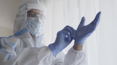 A close up shot of a doctor or healthcare worker in personal protective kit preparing and wearing hand gloves in the interior hospital or clinic setup amid Coronavirus or COVID 19 epidemic or pandemic