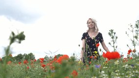 Blonde woman listen a music in headphones in poppy flowers fields in summer