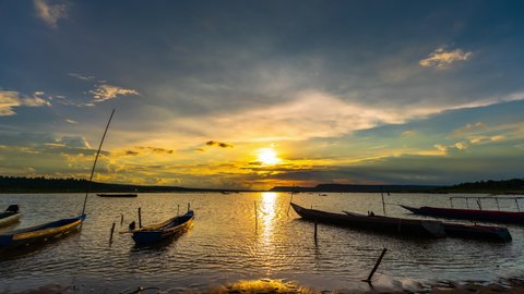 day to night timelapse of wooden boat at banks of the river with sunset in Khonburi, Nahon Ratchasima province, Thailand.