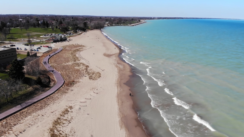 Aerial view people walking dogs on the shores of Lake Michigan in Illinois. People walking dogs on a sandy beach.