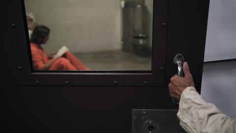 Outside a prison cell as a prisoner inside reads his bible