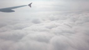 Plane flight through dense fluffy puffs of white cloud at sky. Flying in soft clouds, looking from window