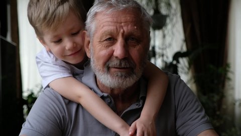 Senoir elderly happy man grandfather with grandson boy looking at camera, smiling and hugging
