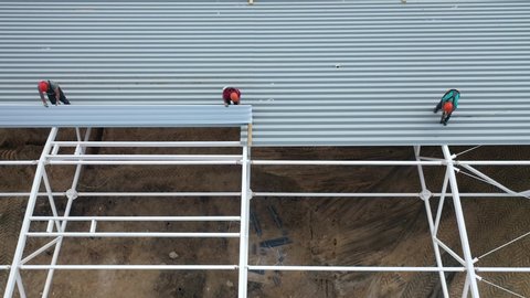 Workers install the roof of a modern frame building. Top view from a drone.