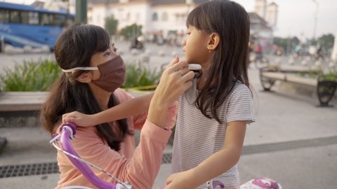 mother help daughter to wearing face masks on new normal. covid 19 virus prevention in the city