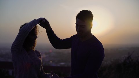 Multi-ethnic dancers couple having fun practising Latin dance moves outdoors against panoramic view at sunset