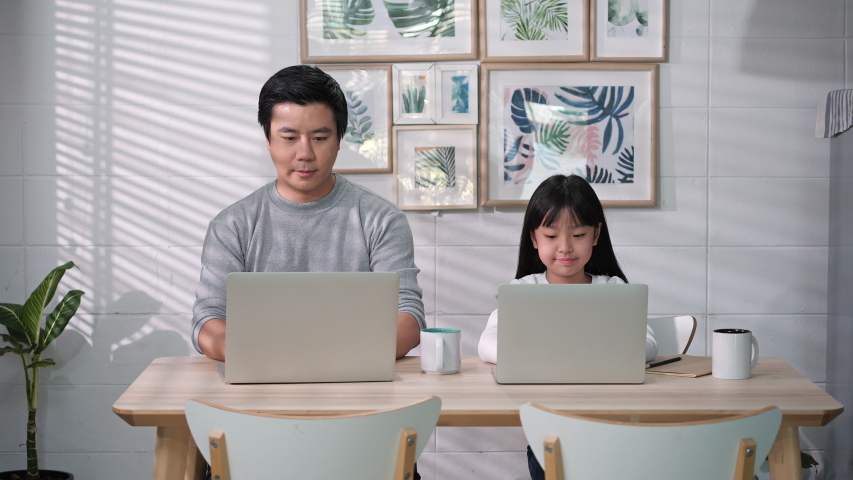 Asian family of businessman working and student girl studying from home. Father and Daughter happy expression with conference online in internet while being quarantine at home. Stay at home family. Royalty-Free Stock Footage #1054147043