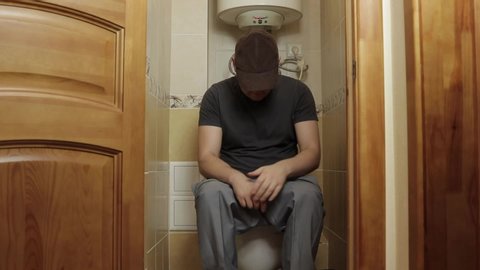 a man sits on the toilet and suffers