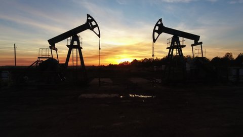 Moving between two working oil pumps against sunset, 4k