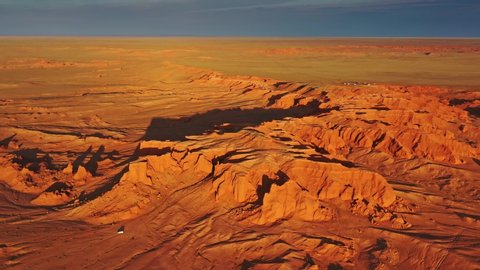 Aerial around view of the Bayanzag flaming cliffs at sunset in Mongolia, found in the Gobi Desert, 4k