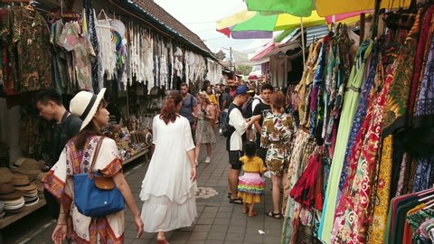 Ubud, Bali, Indonesia - September 5, 2019: Tourists and local people sightseeing and shopping in a colorful open market selling clothing and souvenirs