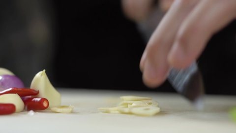 Chef slicing garlic cloves on the cutting board 