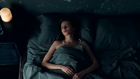 Top View of Woman Trouble Sleeping in Loft Bedroom. Beautiful Young Woman Waking up at Night and Having Bad Headache. Woman with Insomnia. Sleeping Disorder.