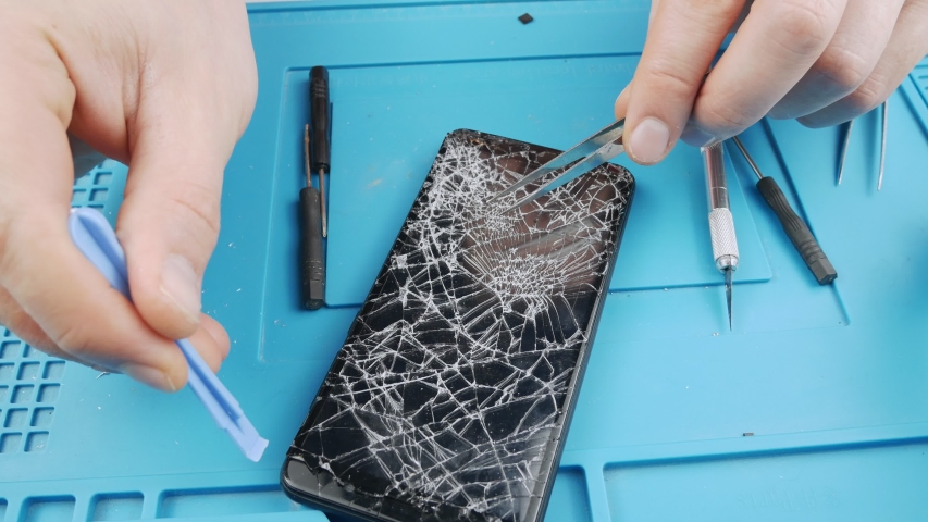Replacement display smartphone.Repair touchscreen.Removes broken phone screen.Cracked screen.Remove the old screen smartphone.Replacement phone repair parts.Broken gadget.Close-up. Royalty-Free Stock Footage #1054164176