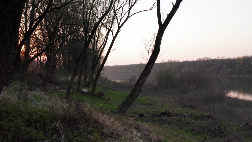 Drone cinematic flying behind trees and capturing sunset over the river. River Sava in Bosnia and Herzegovina has beautiful sunset and nature around river.