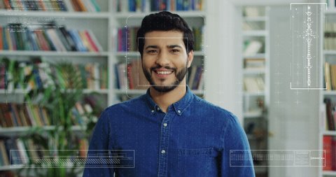 Portrait of young handsome Arabian guy in library with face recognition technology on. Augmented reality. Biometric facial recognition. Close up of Arab male smiling to camera. 3D scanning.