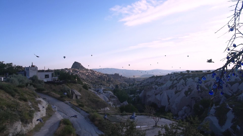 Flock Of Birds Flying With Hot Air Balloons Over The Beautiful Rock Formations In Goreme, Cappadocia, Turkey - wide shot