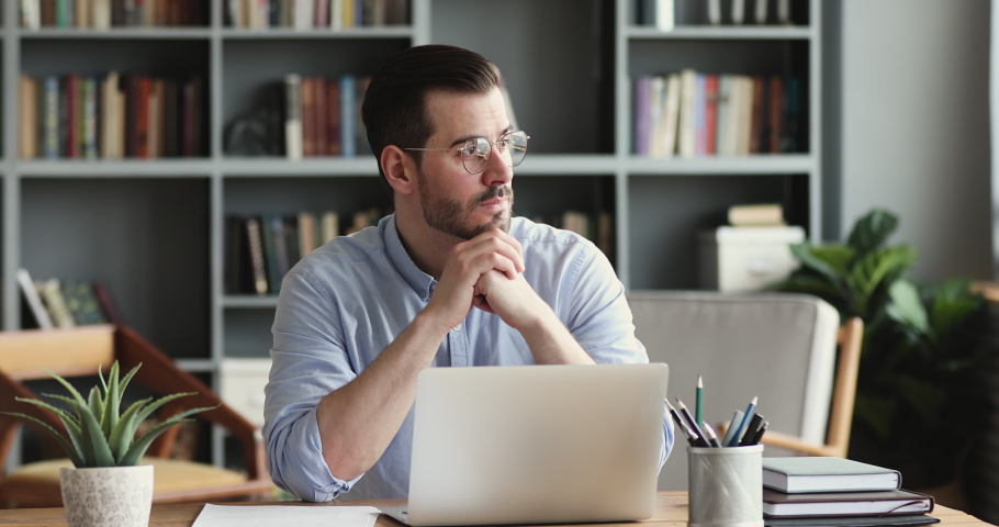 Thoughtful young businessman looking away, considering risks. Focused software developer programmer finding problem solution, writing code on computer. Concentrated manager analyzing market online. | Shutterstock HD Video #1054174040