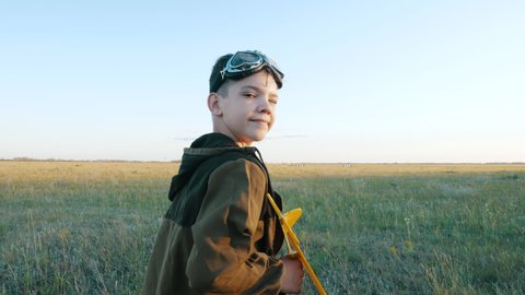 Smiling Child Boy Looking at Camera Plays Funny Game Walking on Field, Launches Toy Airplane to Fly Outdoor at Sunset. Profession Interest, Imagination Freedom, Active Childhood of Little Future Pilot