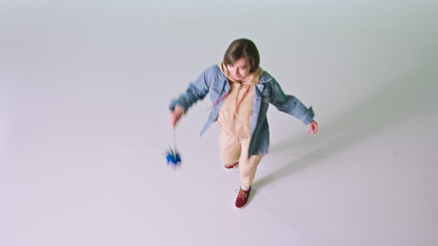 Happy dancing lady with a wind spinner with a short hair in front of the camera in a white background studio