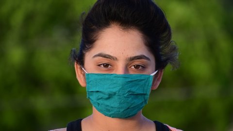Breathing without mask. Young pretty woman stands in the park, takes off the protective mask and starts breathing fresh air. Camera tilts up to the trees. shot in 4k resolution