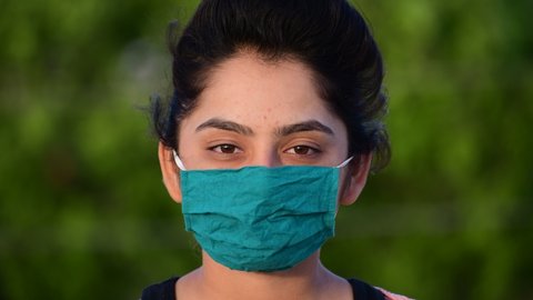 Girl removes medical mask on nature near tree and takes breath. Young woman takes off on mask,Person wears face mask, then removes face mask to protect from virus.shot in 4k resolution.