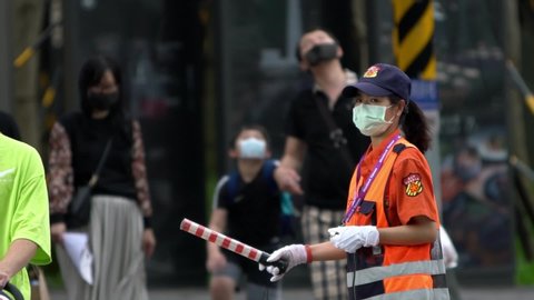 Taipei, Taiwan-31 May, 2020: Slow motion woman traffic surgeon wearing face mask during coronavirus outbreak. People walking in street and used surgical masks for virus infection in public place-Dan