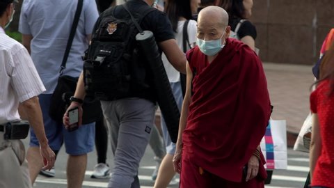 Taipei, Taiwan-04 June, 2020: Slow motion of coronavirus epidemic in China concept. Old asian monk wearing face masks againt Covid19. Spirituality man with medical mask crossing road in city.-Dan