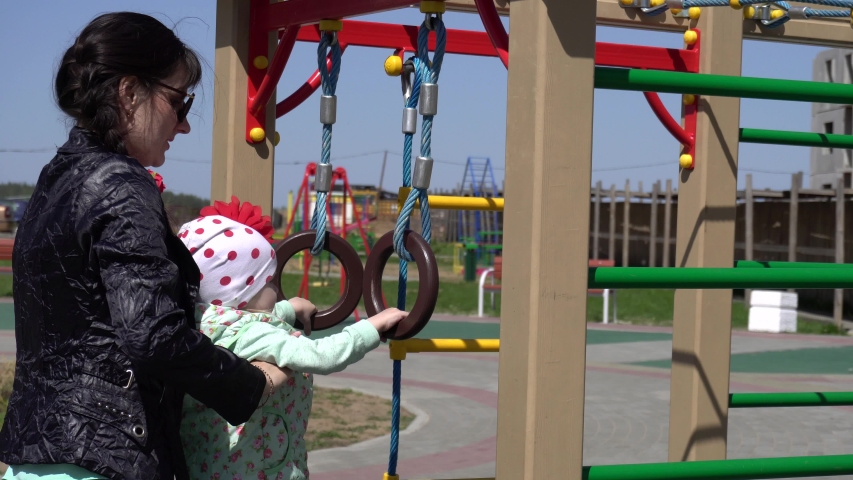 A little cheerful caucasian girl plays with her mom on a new playground. Happy and happy family