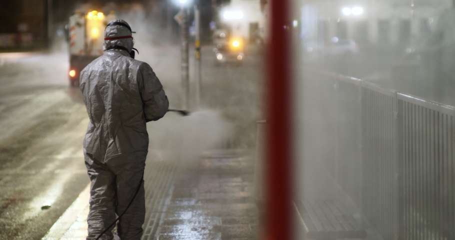 Decontaminating technician in full protective suit disinfects the bus stop at night due to covid-19 pandemic Royalty-Free Stock Footage #1054191467
