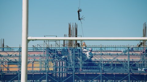 Construction workers on a construction site in Japan building a sports stadium. They are working on scaffolding near a crane