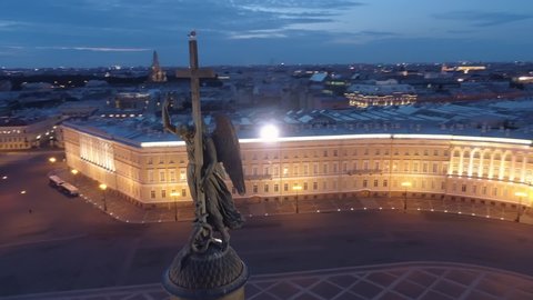 Aerial around angel on cross historic Alexandria column in center of Palace square. St. Petersburg night backlight. Epic central cityscape. Seagull sits on top. Saint Isaac's Cathedral. Travel sight