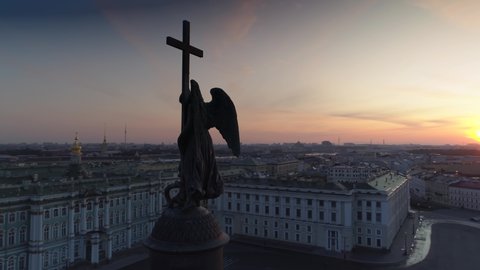 Cinematic angel on cross historic Alexandria column in center of palace square dark silhouette. St. Petersburg. Dramatic sunset sun through sculpture. White night epic central cityscape. Aerial around