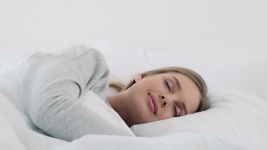 A lovely young woman is sleeping in the white bed at home Royalty-Free Stock Footage #1054205015
