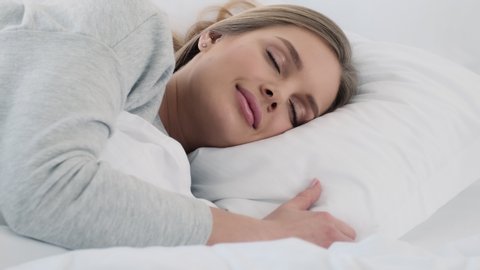 A lovely young woman is sleeping in the white bed at home