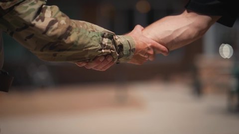 Military man and civilian grabbing arms shaking hands close up slow motion