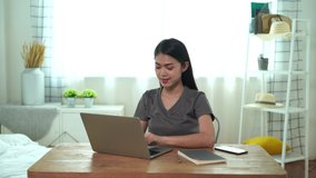 An Asian woman uses a laptop to work at home, Communication on the internet with customers, She stretched her hands to relax after work, Work from home.