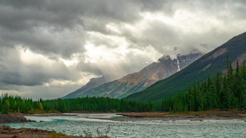 Alaskan Mountain Range With Glacier River Driftwood Cropped Fast Rushing river with drift wood and stone islands at the end of fall in the Canadian and alaskan Rocky Mountains in Banff Time Lapse 4K