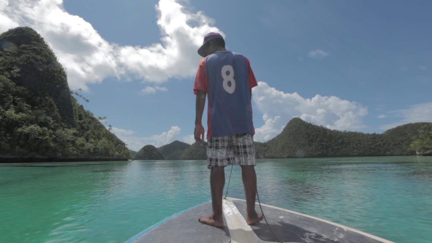 Raja Ampat Islands, West Papua, Indonesia - CIRCA 2020: Papuan People Papuans Melanesians Man Guiding The Boat in Wayag