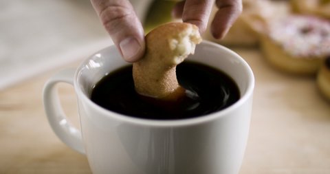 Dunking  doughnut into a cup of coffee. Slow-motion doughnut dunk into cup of coffee. Shot in 4k. 