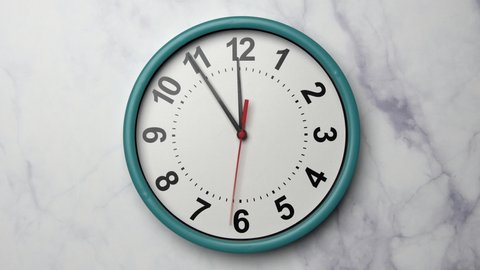 The Time On The Clock Twelve. Turquoise Clock With The Red Arrow With The Arabic Numerals On An Marble Stone Wall Background.