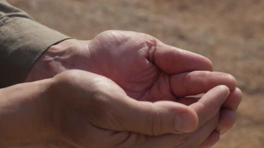 stream of fresh drinking water pouring into human hands, drought land on the background. dry farmland, lack of water. Clean water splashing on hands of the poor rural man. ecology concept Royalty-Free Stock Footage #1054228010