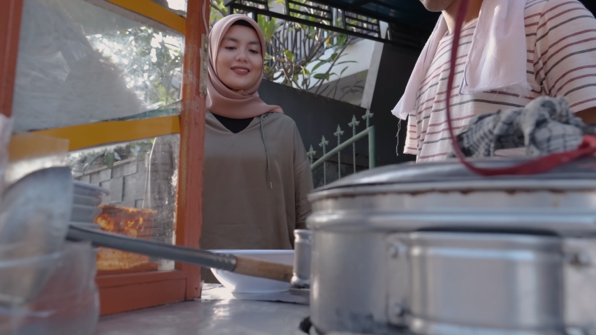street food vendor handing a bowl of bakso or meatball to customer