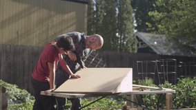 A father and son wearing safety glasses build a wooden skateboard ramp in the backyard - Powered by Shutterstock - Get 15% off with code: PIKWIZARD15