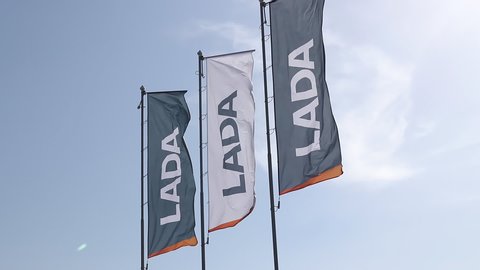 Minsk, Belarus, 06.2020 three corporate flags with logo lada on a blue sky background with clouds. sign of a dealership center selling new cars