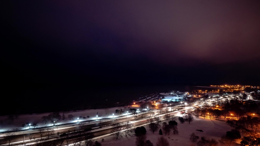 Beautiful aerial morning sunrise timelapse of the Chicago Lakefront along Lake Michigan with traffic flying by on Lake Shore Drive as night turns to day.