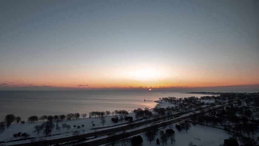 Beautiful aerial morning sunrise timelapse of the Chicago Lakefront along Lake Michigan with traffic passing by on Lake Shore Drive as night turns to day as the sun comes up over clouds on the horizon