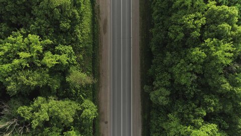 Empty road endless asphalt straight freeway in green dense forest / Aerial top down view, Highway trip without cars at summer sunset